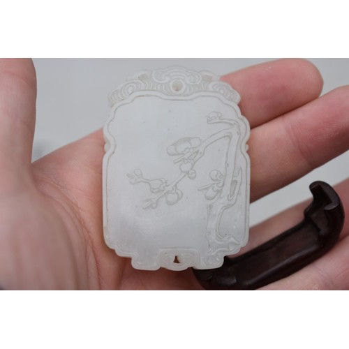 1251 - A Chinese carved pale celadon jade pendant, probably Qing, decorated in shallow relief with flowerin... 