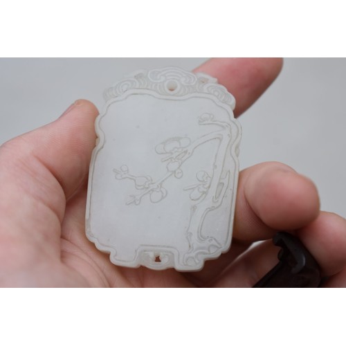 1251 - A Chinese carved pale celadon jade pendant, probably Qing, decorated in shallow relief with flowerin... 