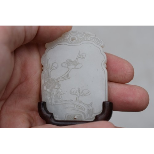 1251 - A Chinese carved pale celadon jade pendant, probably Qing, decorated in shallow relief with flowerin... 