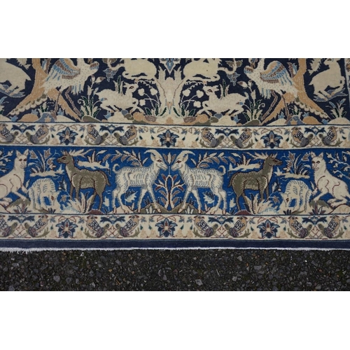 1093a - A Qum silk rug, having central field decorated with trees and animals on a blue ground, with animals... 