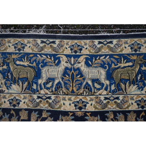 1093a - A Qum silk rug, having central field decorated with trees and animals on a blue ground, with animals... 