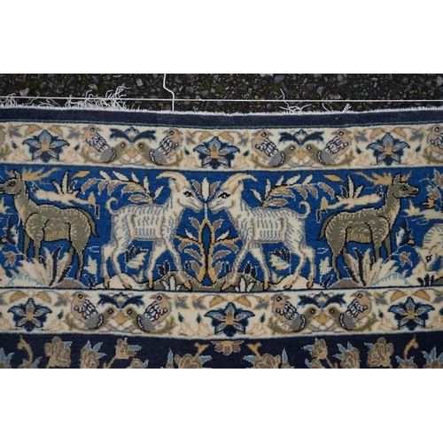 1093a - A Qum silk rug, having central field decorated with trees and animals on a blue ground, with animals... 