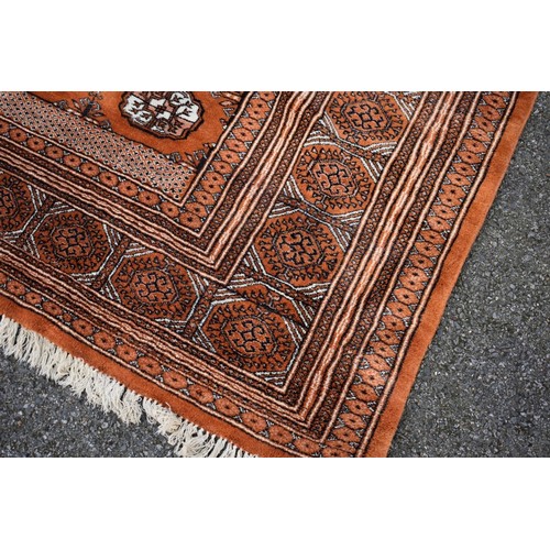 1094a - A Bokhara carpet, having repeated design to central field on an orange ground, 343cm x 247cm. ... 