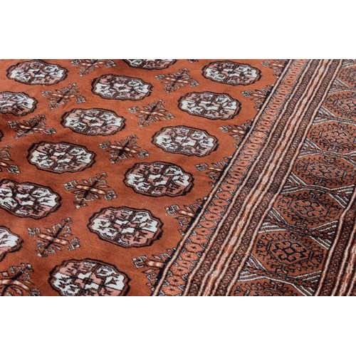 1094a - A Bokhara carpet, having repeated design to central field on an orange ground, 343cm x 247cm. ... 