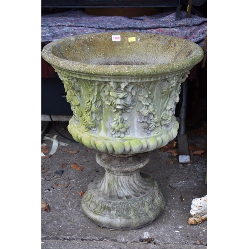 1068 - A concrete garden urn decorated with lion heads, 52.5cm wide x 62cm high.Collection of this lot is s... 