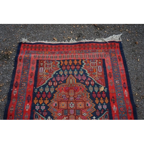 1100 - A long Tribal runner, having seven central medallions, with floral borders on a red and blue ground,... 