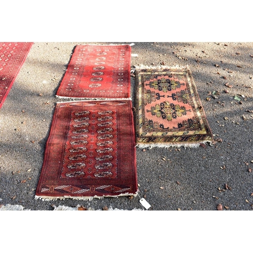 1105 - Two small Bokhara rugs; together with another small rug having geometric decoration.... 