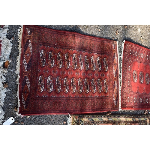 1105 - Two small Bokhara rugs; together with another small rug having geometric decoration.... 