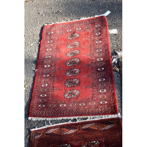1105 - Two small Bokhara rugs; together with another small rug having geometric decoration.... 