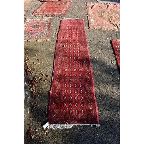 1106 - A Bokhara runner on a red ground, 262 x 56cm.