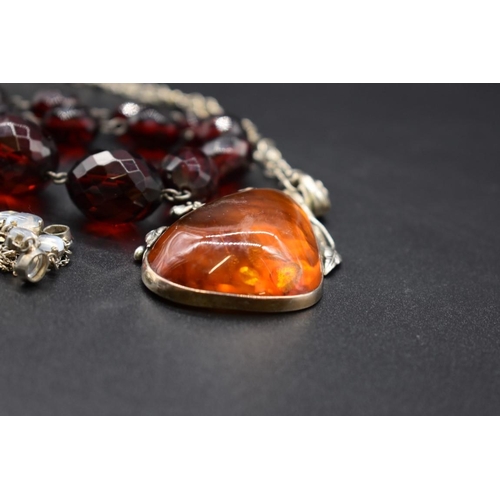 223 - A graduated and faceted cherry amber bead necklace, 43cm, 49g; together with an amber pendant, on ch... 