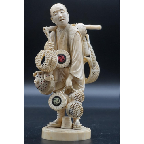 1298 - A Japanese carved ivory okimono, Meiji, depicting a basket seller, seal mark on inset tablet, 18cm h... 