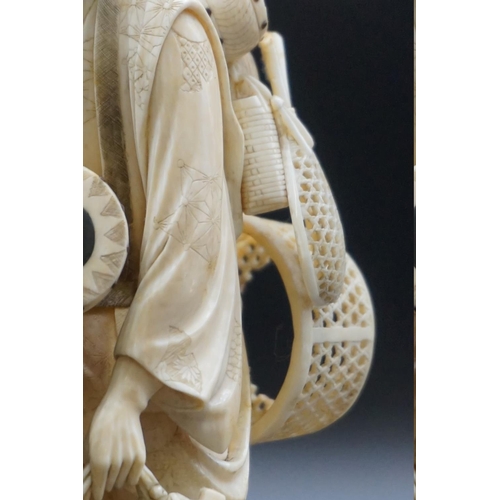 1298 - A Japanese carved ivory okimono, Meiji, depicting a basket seller, seal mark on inset tablet, 18cm h... 