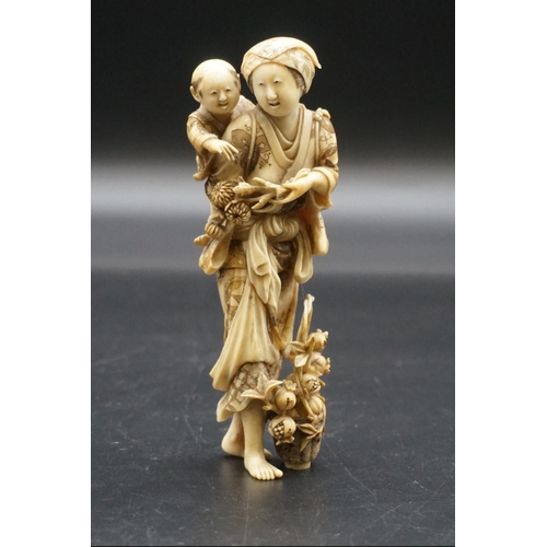 1303 - A good Japanese carved ivory okimono figure group, 19th century, depicting a standing mother, with a... 