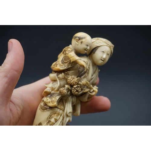 1303 - A good Japanese carved ivory okimono figure group, 19th century, depicting a standing mother, with a... 