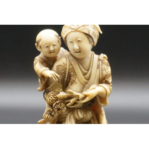 1303 - A good Japanese carved ivory okimono figure group, 19th century, depicting a standing mother, with a... 