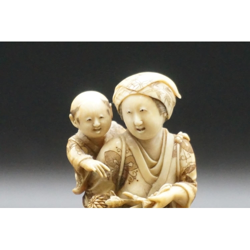 1303 - A good Japanese carved ivory okimono figure group, 19th century, depicting a standing mother, with a... 