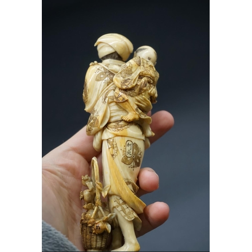 1303 - A good Japanese carved ivory okimono figure group, 19th century, depicting a standing mother, with a... 