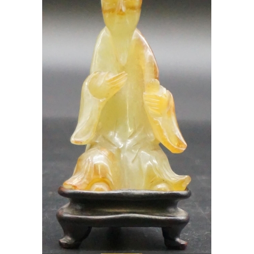 1311 - A Chinese carved mottled green jade seated figure, 8.7cm high, on fitted hardwood stand.... 