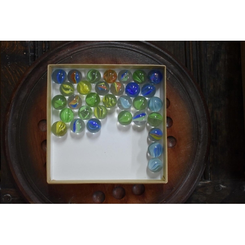 1384 - Two solitaire boards, including a yew example; and a quantity of glass marbles.