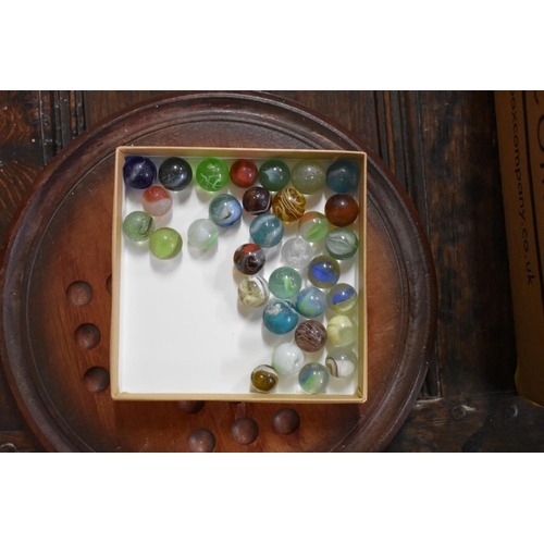 1384 - Two solitaire boards, including a yew example; and a quantity of glass marbles.