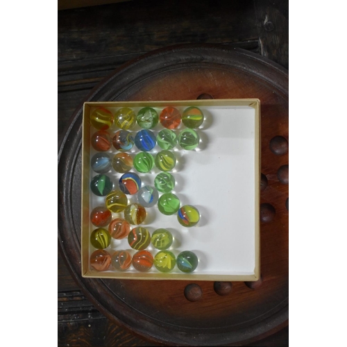 1384 - Two solitaire boards, including a yew example; and a quantity of glass marbles.