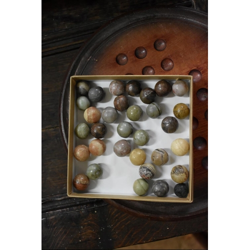 1384 - Two solitaire boards, including a yew example; and a quantity of glass marbles.