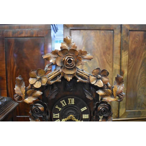 1441 - A large 19th century Black Forest carved walnut cuckoo clock, striking on a gong, 59cm high, with as... 