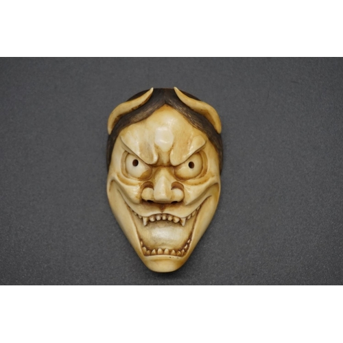 1243 - A good Japanese carved ivory 'Oni' Noh mask okimono, 19th century, 6.8cm.