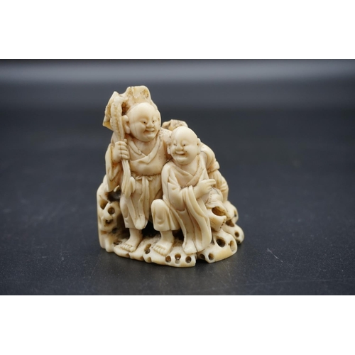 1246 - A Japanese carved ivory okimono, 19th century, depicting two figures by a rocky outcrop, 6cm high.... 