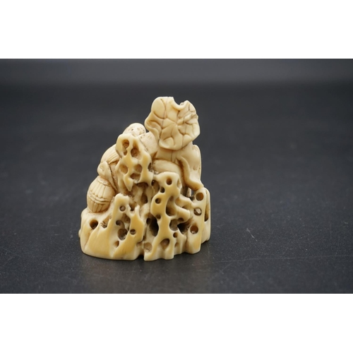 1246 - A Japanese carved ivory okimono, 19th century, depicting two figures by a rocky outcrop, 6cm high.... 