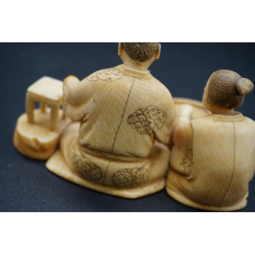 1248 - A Japanese carved ivory okimono, Meiji, depicting two seated figures, one holding a brush, signed, s... 