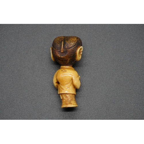 1250 - An unusual Japanese carved ivory netsuke, Meiji, depicting a standing monkey in robes, with inset ey... 