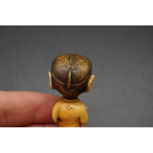 1250 - An unusual Japanese carved ivory netsuke, Meiji, depicting a standing monkey in robes, with inset ey... 