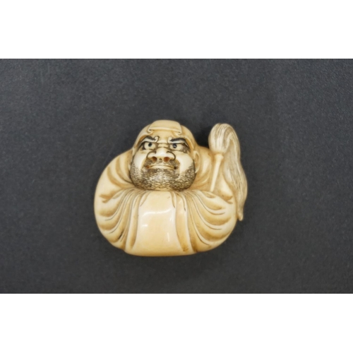 1254 - A good Japanese carved ivory netsuke, by Masahiro, Edo, depicting Daruma wall-gazing, with inset eye... 