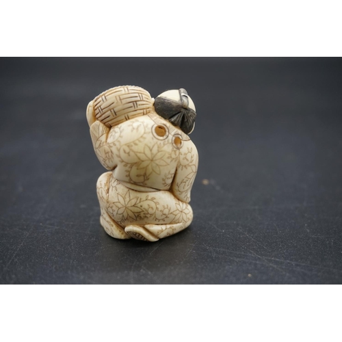 1256 - A Japanese carved ivory netsuke, early 20th century, depicting a man with a basket of fruit, 4.5cm h... 