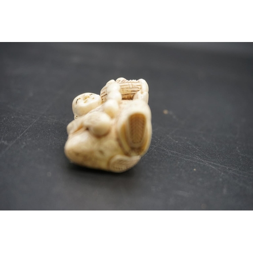 1256 - A Japanese carved ivory netsuke, early 20th century, depicting a man with a basket of fruit, 4.5cm h... 