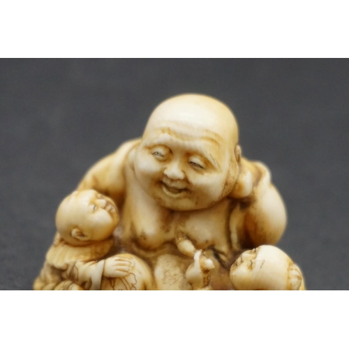 1280 - A good Japanese carved ivory netsuke, Edo, depicting Hotei and two Karako, signed, 4cm high.... 