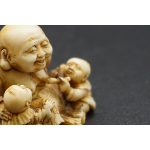 1280 - A good Japanese carved ivory netsuke, Edo, depicting Hotei and two Karako, signed, 4cm high.... 