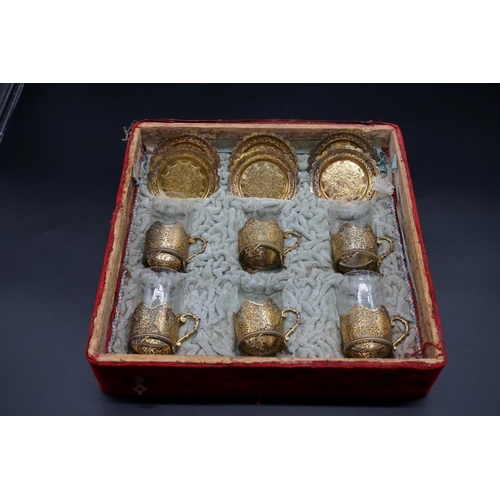 74 - A cased set of six Turkish gilt metal coffee glass holders and saucers, (lacking two glasses).... 