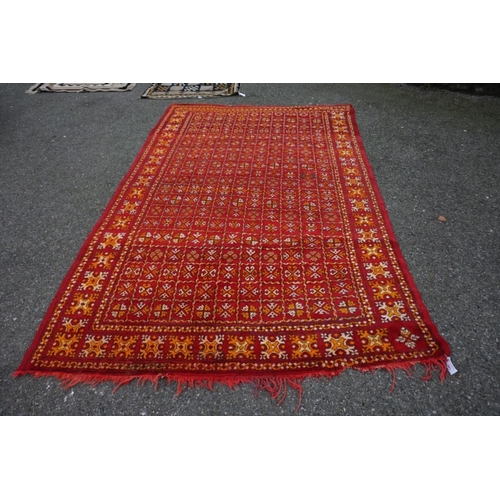 1064 - An old rug, having allover geometric decoration on a red ground, 298cm x 190cm. ... 