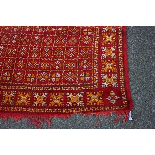 1064 - An old rug, having allover geometric decoration on a red ground, 298cm x 190cm. ... 