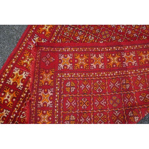 1064 - An old rug, having allover geometric decoration on a red ground, 298cm x 190cm. ... 