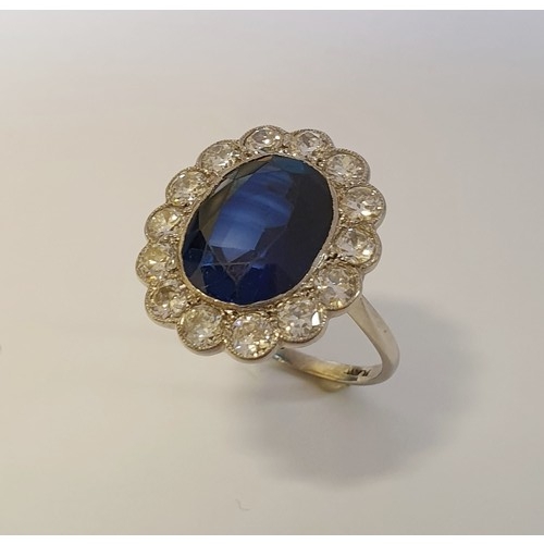 295 - A 1930s blue gemstone and diamond cluster ring, stamped Plat, surrounded by fourteen collet set diam...
