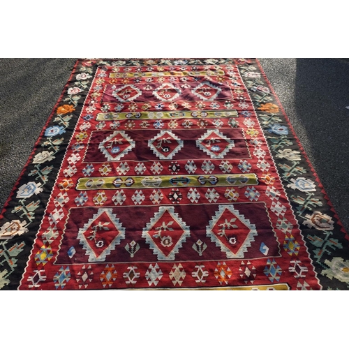 1077 - A Caucasian flatweave rug, having nine diamond medallions to central field, with floral borders, 295... 