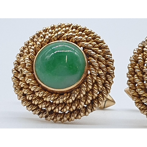 23 - (NB) A pair of yellow metal cufflinks, each set with a cabochon jade to centre with a triple rope bo... 