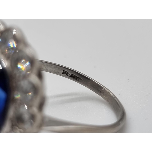 295 - A 1930s blue gemstone and diamond cluster ring, stamped Plat, surrounded by fourteen collet set diam... 