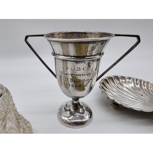 621 - A quantity of silver, to include: a silver shell shaped butter dish; a silver trophy cup; and a silv... 