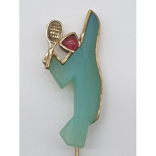 64 - (NB) A yellow metal stylized tennis player lapel pin, stamped 585, set with green chalcedony and cab... 