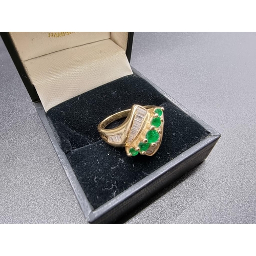 699 - An emerald and diamond crossover ring, set five graduated emeralds, stamped '14Kt', size P.... 